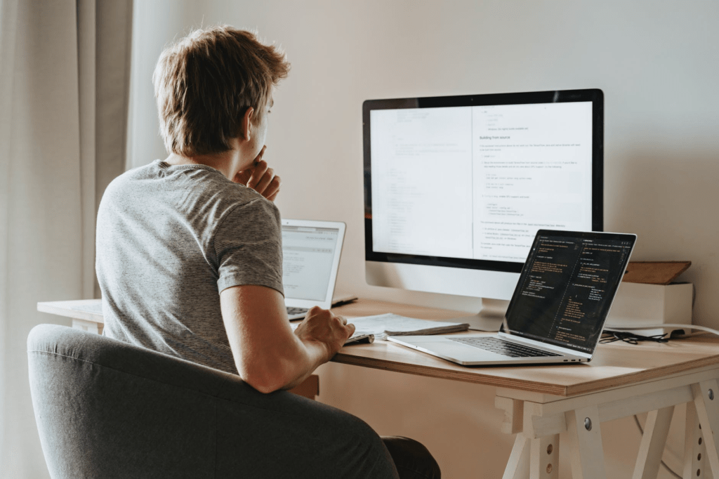 A man doing software programming with multiple laptops