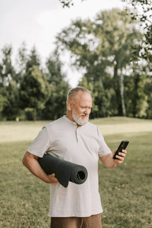 an elderly person using a mobile phone while holding a yoga mat