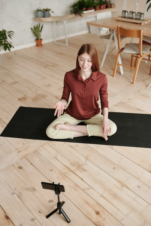 woman watching her mobile while sitting on a yoga mat