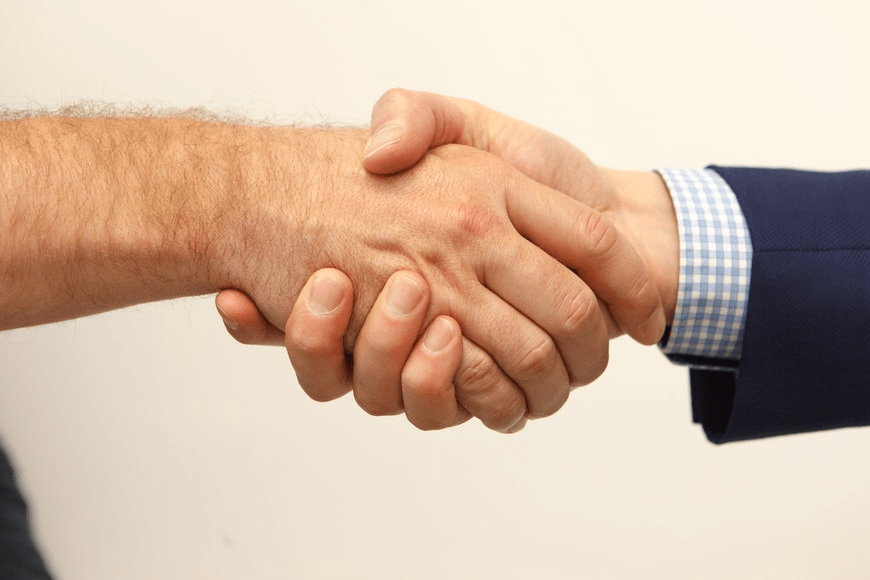 People shaking hands over an agreement over the delivery of a software project.